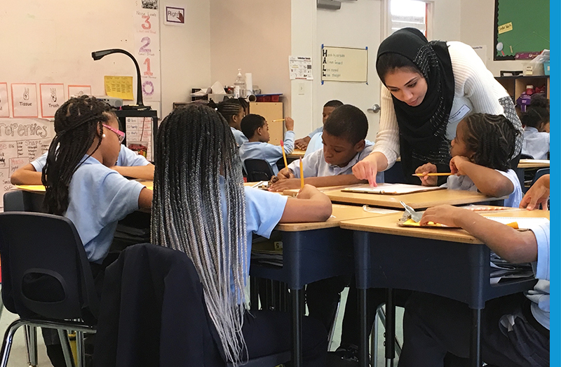 teacher leans over table to assist students